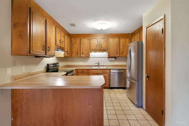 a kitchen with stainless steel appliances granite countertop a refrigerator a sink and a stove