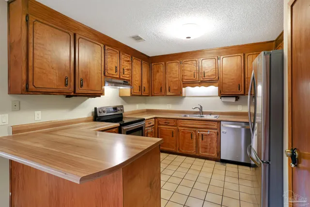 a kitchen with stainless steel appliances granite countertop a sink stove refrigerator and cabinets