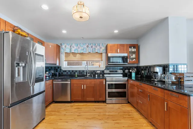 a large kitchen with stainless steel appliances granite countertop a refrigerator and a stove top oven