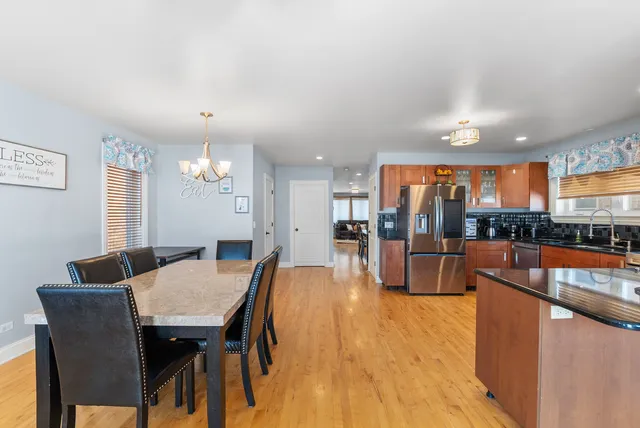 a dining hall with stainless steel appliances kitchen island granite countertop a dining table and chairs