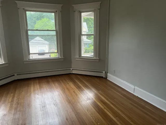 an empty room with wooden floor and windows