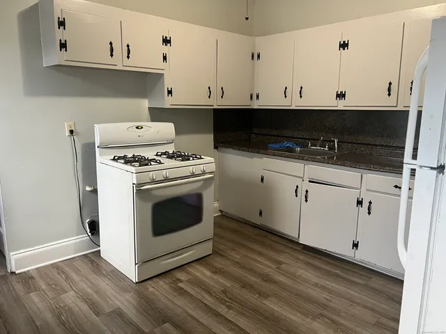 a view of kitchen with stainless steel appliances granite countertop white cabinets and a stove a oven with white countertops