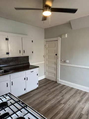 a kitchen with granite countertop a stove cabinets and wooden floor