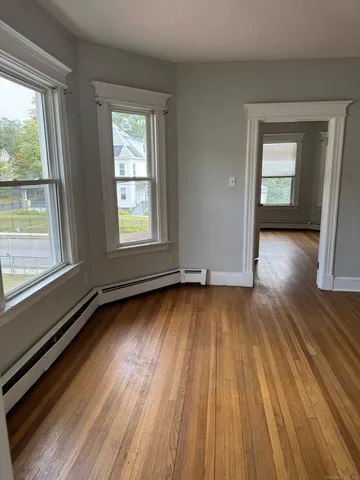 a view of an empty room and wooden floor and a window