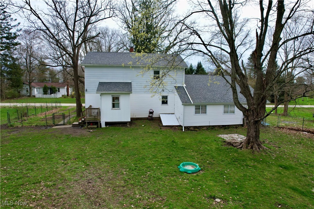 8195 Nichols Road Windham, OH 44288 - Photo 34 of 41 Back of house featuring a yard, roof with shingles, a chimney, and fence