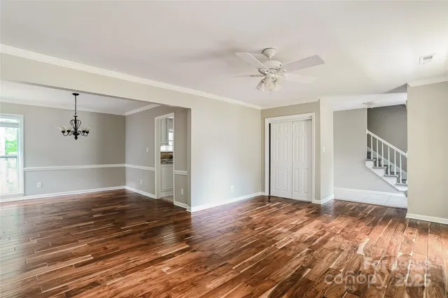 a view of an empty room with window and wooden floor