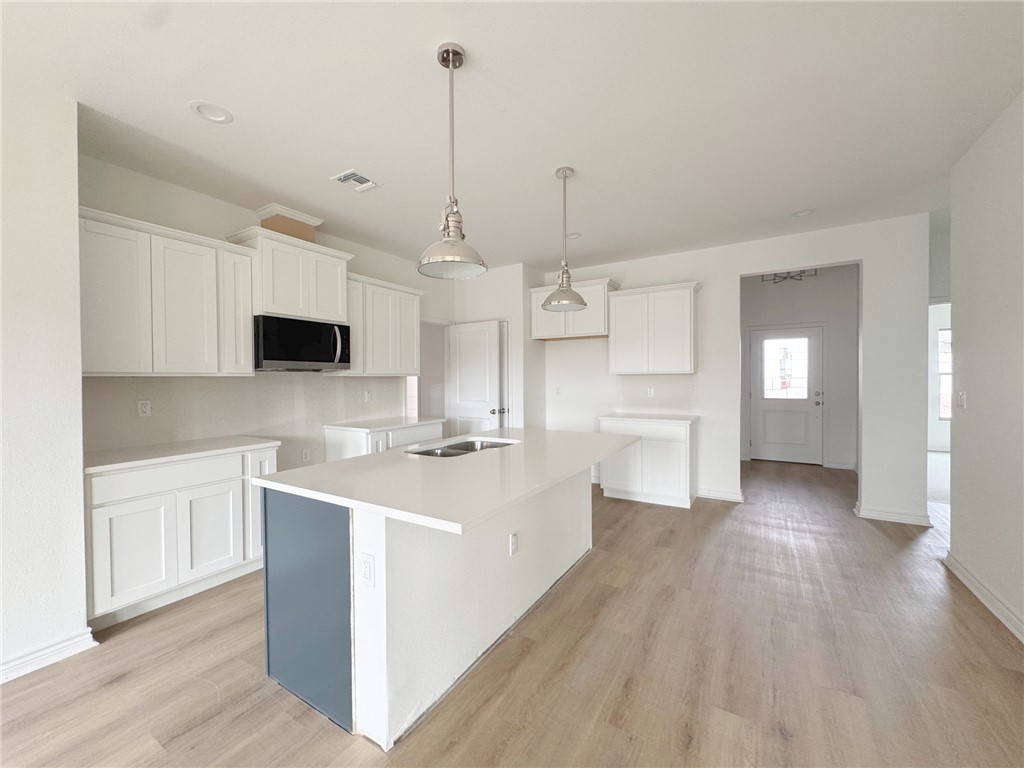2105 Fury Portland, TX 78374 - Photo 15 of 23 a kitchen with stainless steel appliances kitchen island granite countertop a sink a microwave a refrigerator and white cabinets