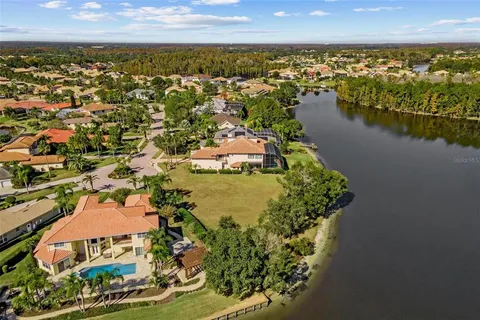an aerial view of residential houses with outdoor space and lake view in back
