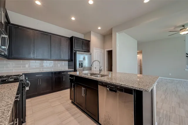 a kitchen with stainless steel appliances granite countertop a sink a stove and a refrigerator