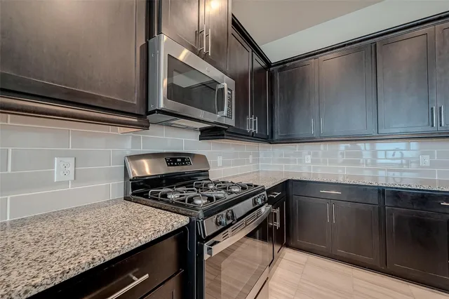 a kitchen with stainless steel appliances granite countertop a sink stove and microwave
