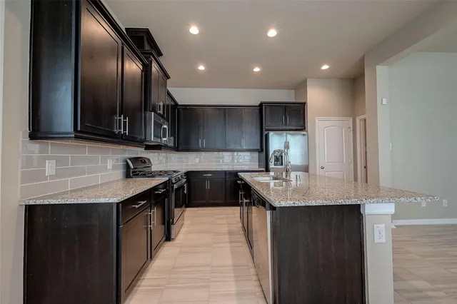 a kitchen with stainless steel appliances granite countertop a sink stove and refrigerator
