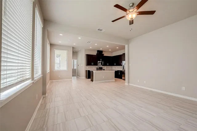 a view of an empty room with a window and a kitchen