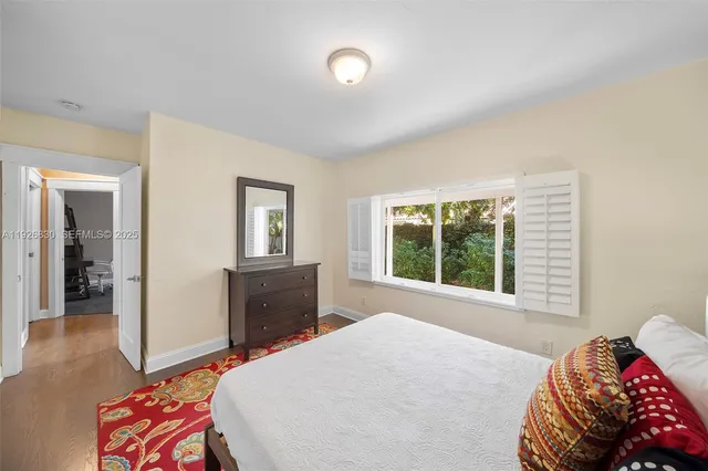 a bedroom with a bed and a dresser with wooden floor