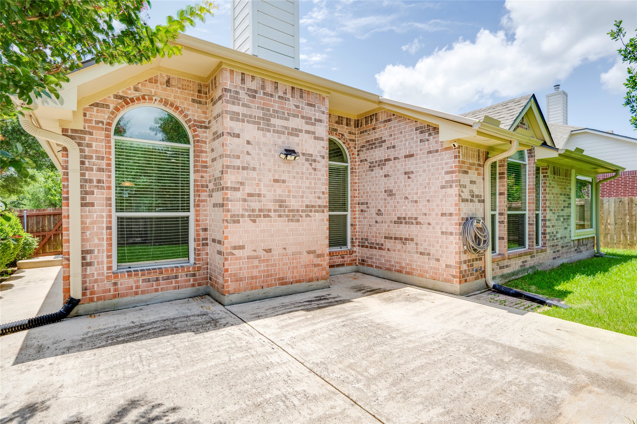 1813 Nelson Ranch Loop Cedar Park, TX 78613 - Photo 37 of 39 A spacious concrete patio awaits outdoor enjoyment, adjacent to a charming brick exterior with arched windows.