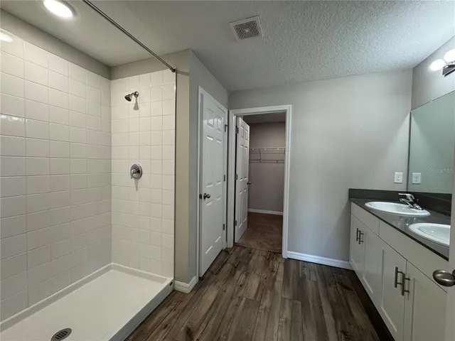 a spacious bathroom with a granite countertop sink toilet a mirror and shower