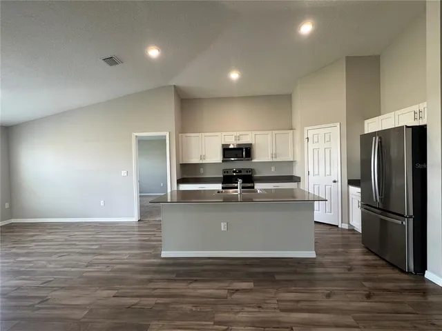 a large kitchen with stainless steel appliances wooden floor and a refrigerator