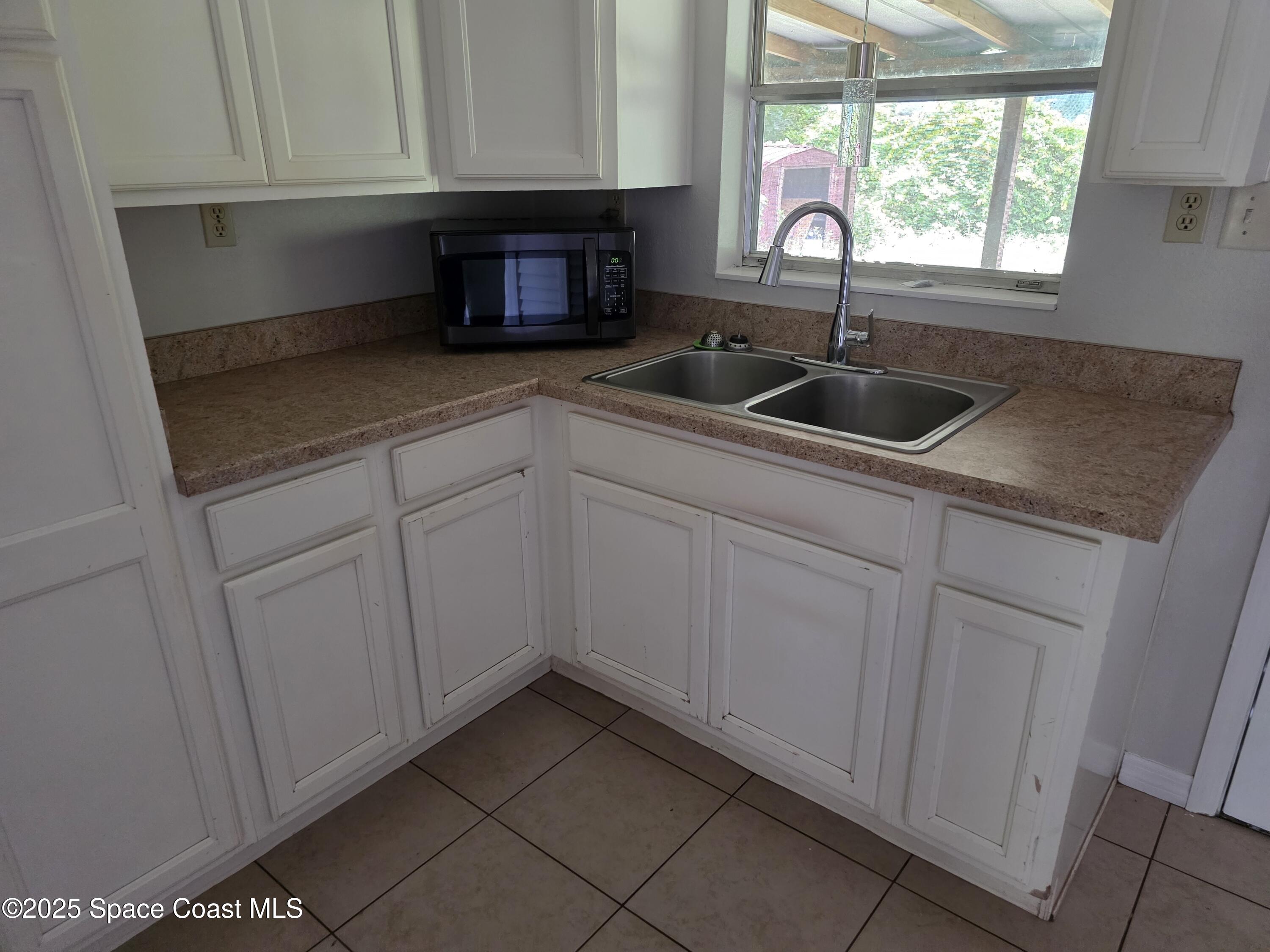 7160 Bevil Avenue Cocoa, FL 32927 - Photo 3 of 10 a kitchen with granite countertop white cabinets and sink