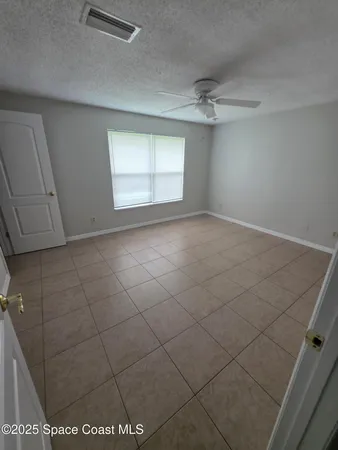 an empty room with windows and ceiling fan