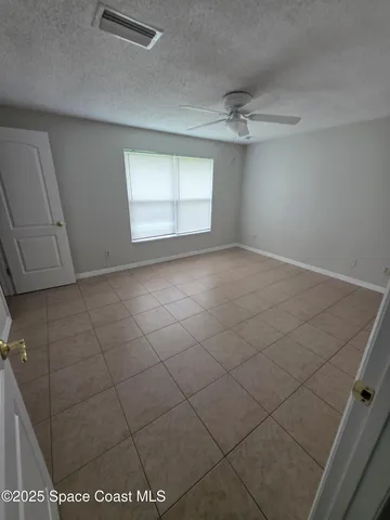 an empty room with windows and ceiling fan