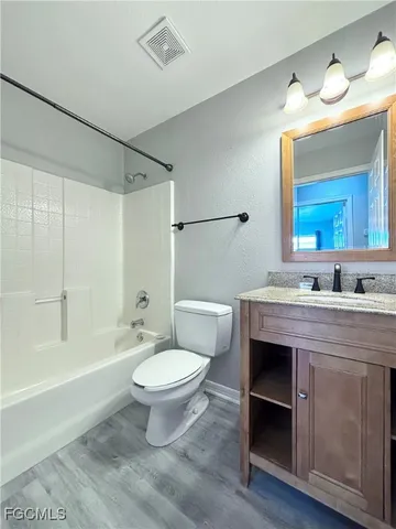a view of an empty room with window a ceiling fan and wooden floor