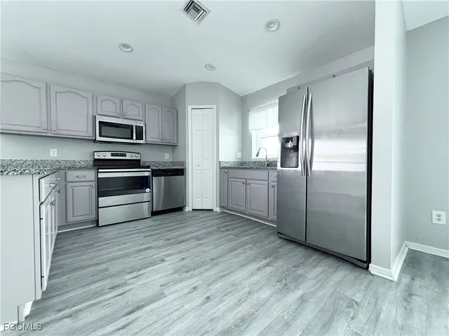 a kitchen with granite countertop a refrigerator and a stove top oven
