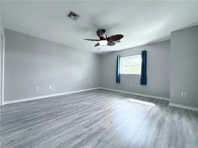 a view of an empty room with a window and wooden floor