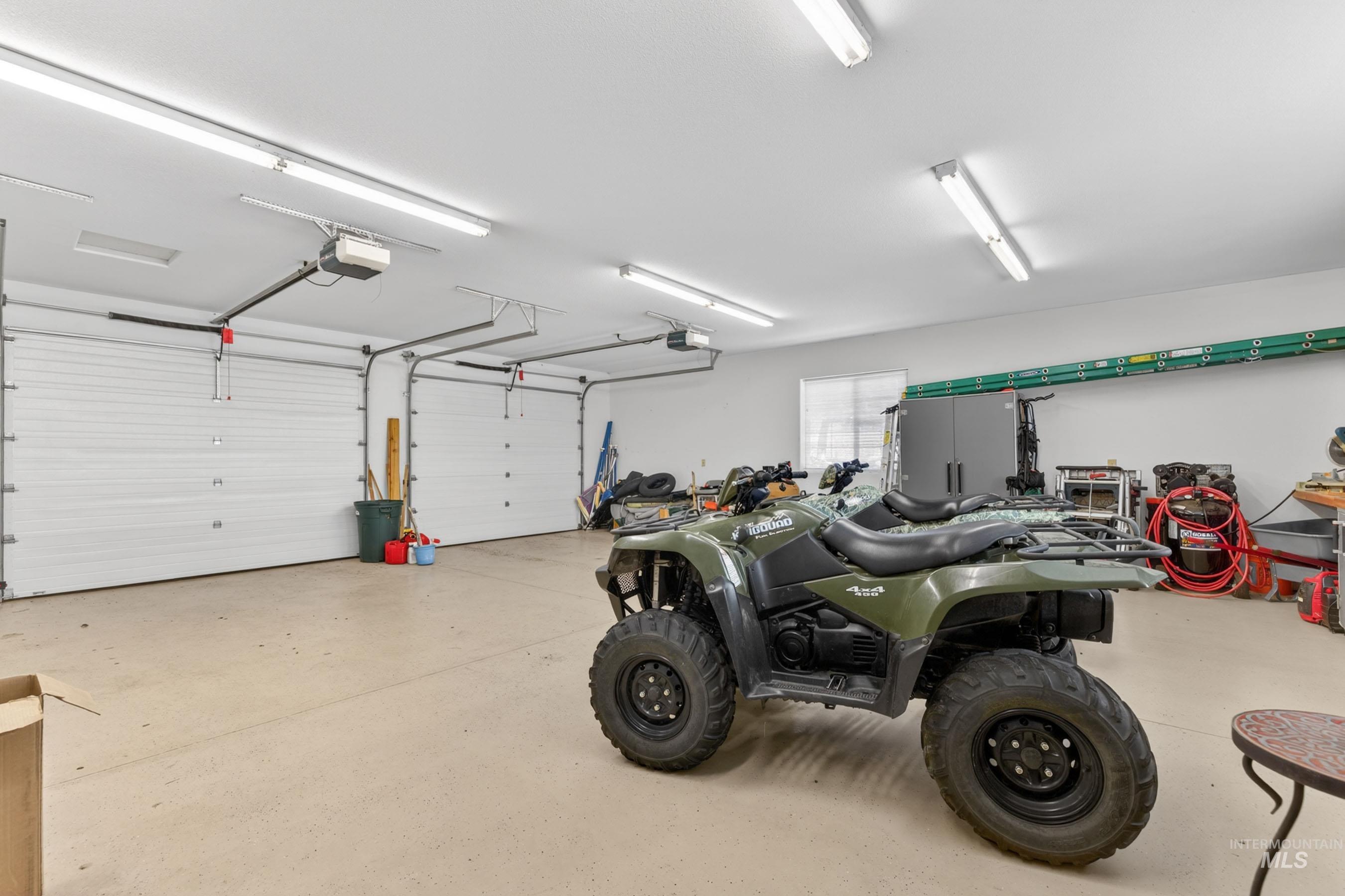 113 Deford Road White Bird, ID 83554 - Photo 38 of 49 Spacious garage featuring two overhead doors, ample overhead lighting, a finished concrete floor, and a large window providing natural light