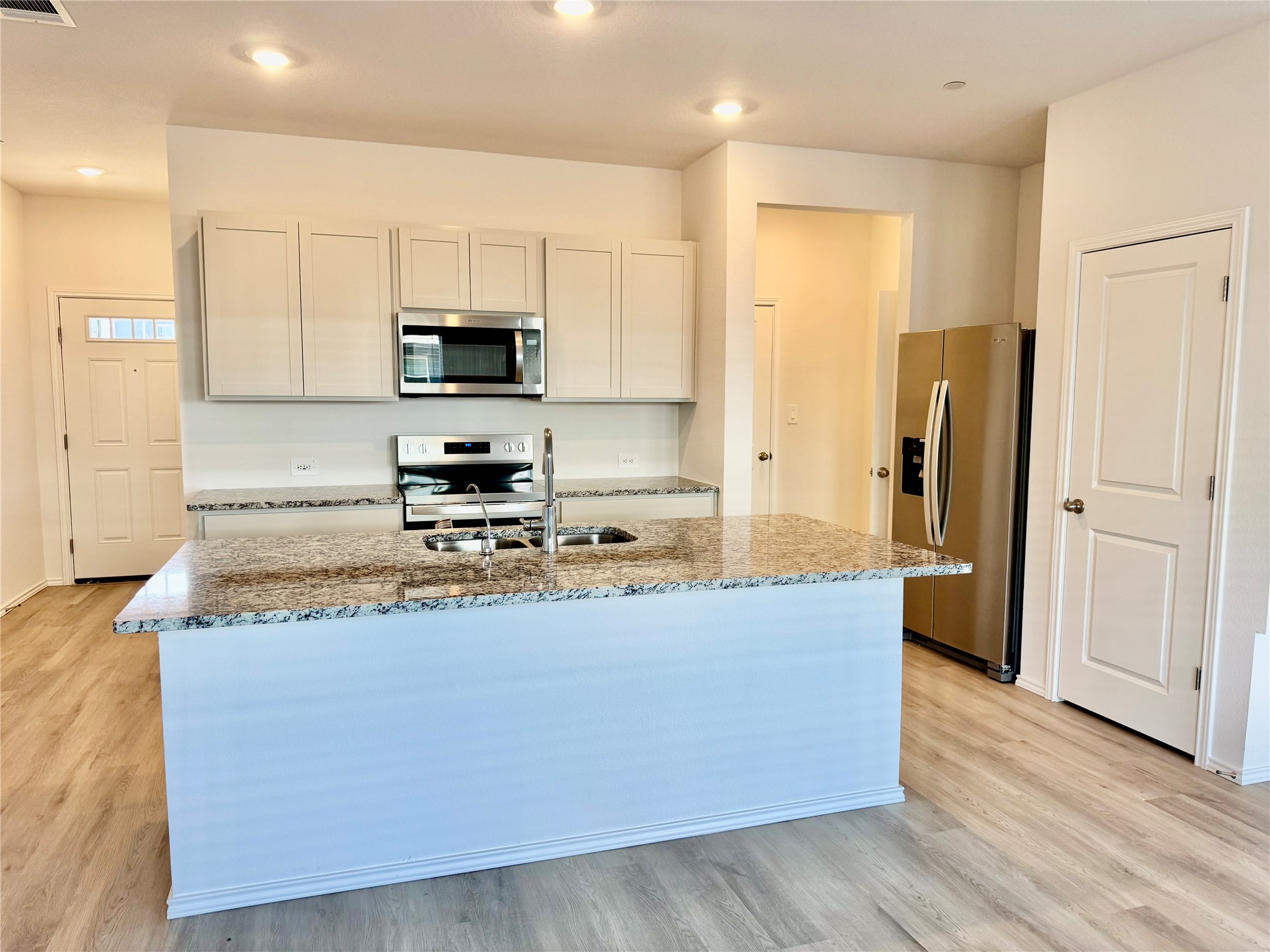 105 Calcite Road, Unit 2 Kyle, TX 78640 - Photo 2 of 7 Kitchen featuring light stone counters, stainless steel appliances, and white cabinetry