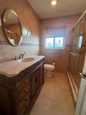 a bathroom with a granite countertop sink a mirror and a toilet