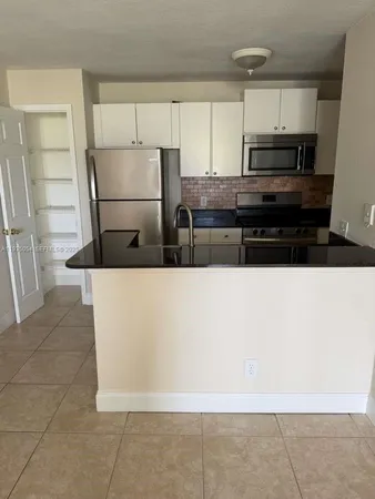 a view of kitchen with refrigerator and cabinets
