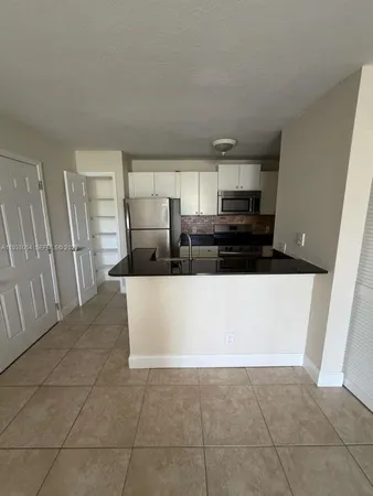 a living room with stainless steel appliances a refrigerator a sink a stove top oven and a counter top space