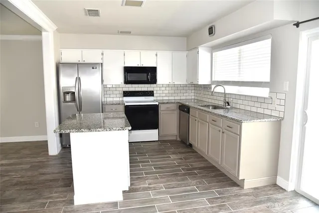 a kitchen with stainless steel appliances kitchen island granite countertop a sink stove refrigerator and cabinets