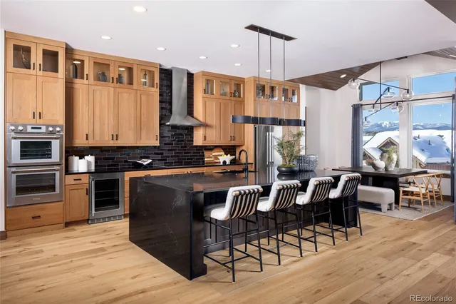 a kitchen with stainless steel appliances granite countertop a stove top oven a dining table and chairs with wooden floor