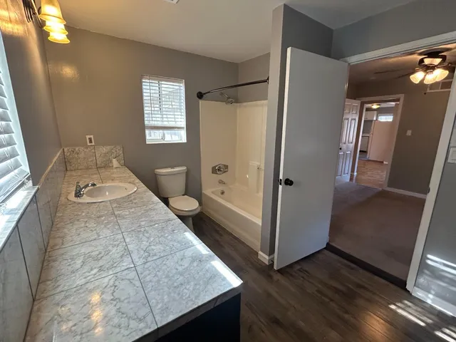 a bathroom with a granite countertop sink a mirror and shower