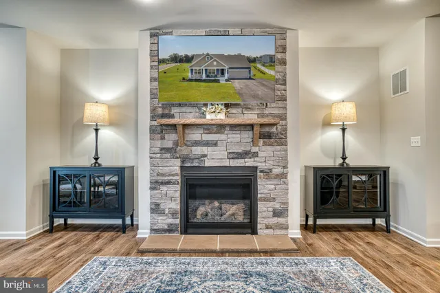 a kitchen with stainless steel appliances kitchen island granite countertop a sink a stove a refrigerator and white cabinets with wooden floor