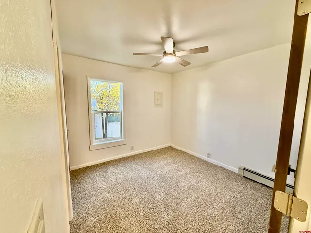 an empty room with windows and ceiling fan