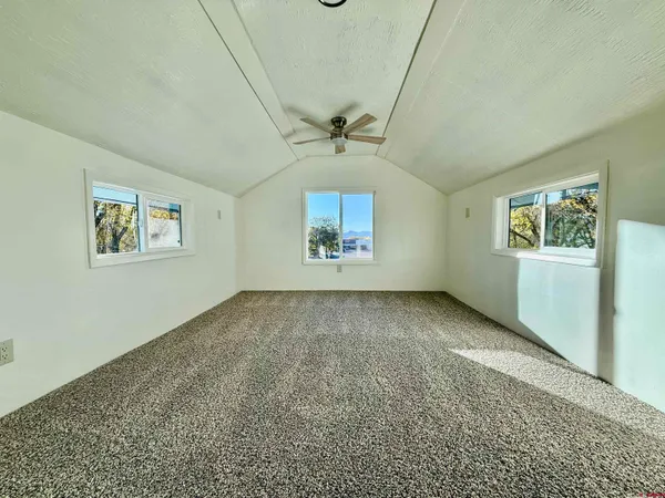 an empty room with windows and ceiling fan