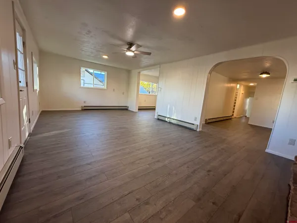 an empty room with wooden floor and windows