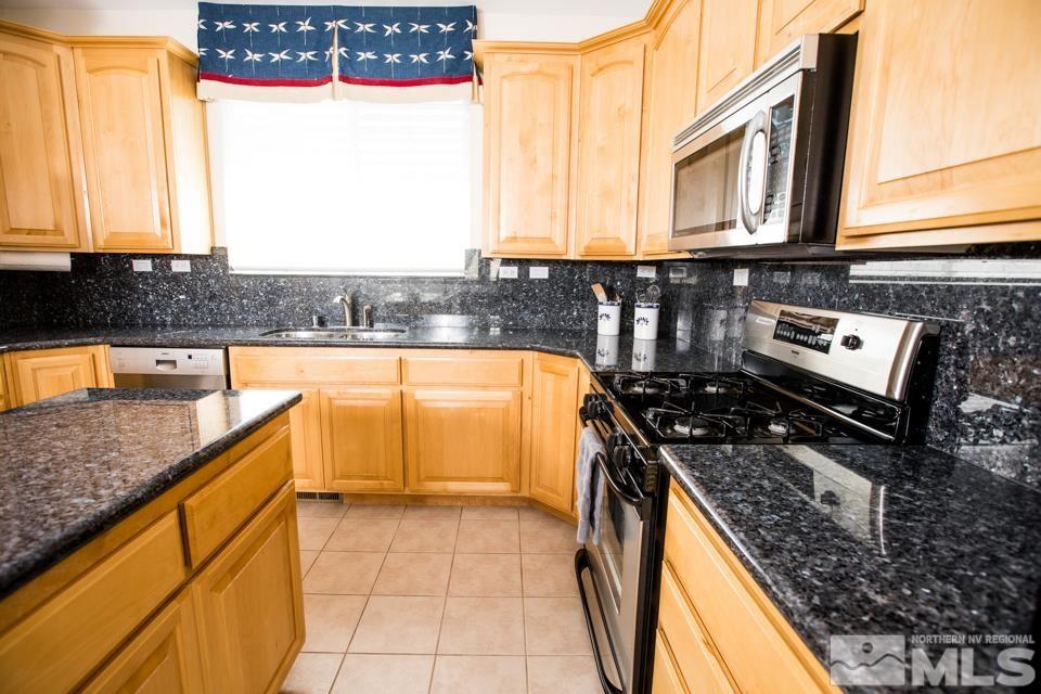 2456 Genoa Meadows Circle Genoa, NV 89411 - Photo 23 of 24 a kitchen with stainless steel appliances granite countertop a stove a sink and a microwave