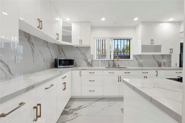 a kitchen with granite countertop cabinets stainless steel appliances a sink and a window