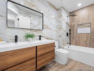 8563 98th Street Queens, NY 11421 - Photo 12 of 16 Bathroom featuring double vanity, tile walls, a combined bath / shower with marble appearance, and recessed lighting