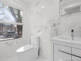 8563 98th Street Queens, NY 11421 - Photo 7 of 16 Half bath with stone wall, vanity, and light marble finish floors