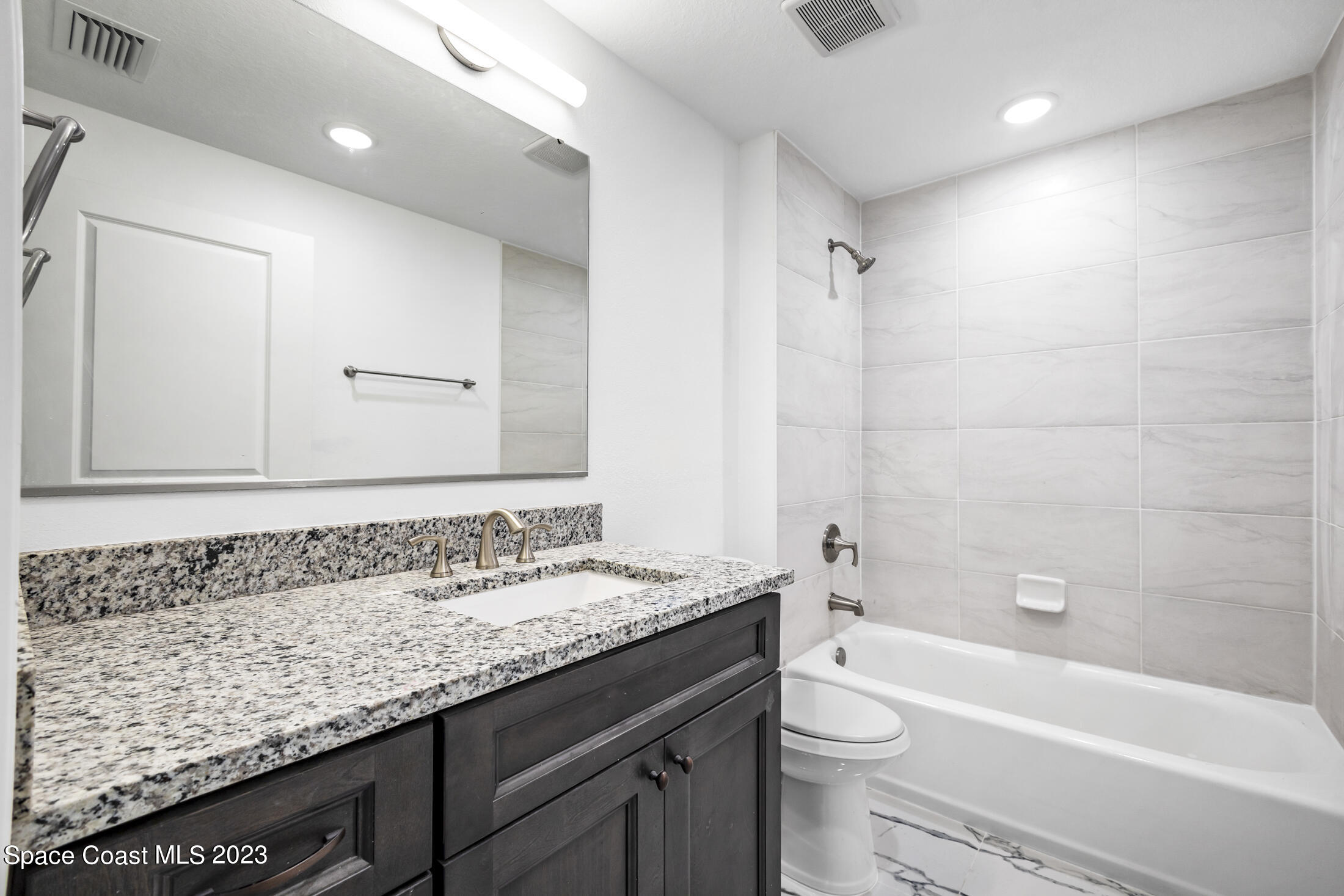 735 Pilot Lane, Unit 313 Merritt Island, FL 32952 - Photo 9 of 20 a bathroom with a granite countertop sink a toilet and bathtub