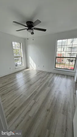an empty room with wooden floor ceiling fan and windows