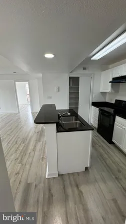 a living room with stainless steel appliances kitchen island granite countertop a refrigerator a stove top oven and wooden floor