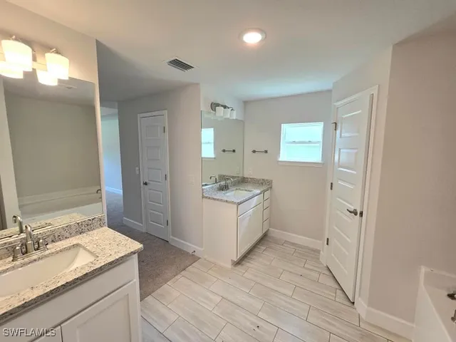 a spacious bathroom with a granite countertop sink a mirror and a shower