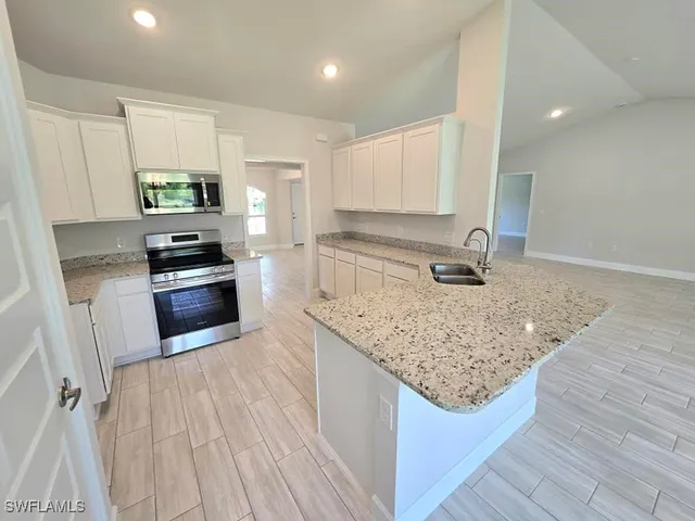 a kitchen with granite countertop a sink stove and refrigerator