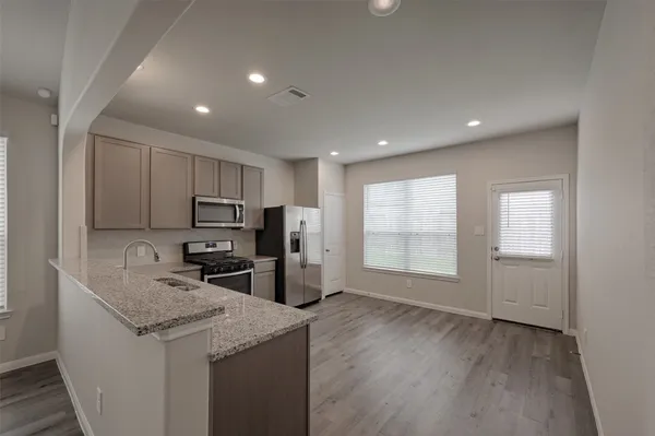 a kitchen with stainless steel appliances granite countertop a sink stove refrigerator and microwave