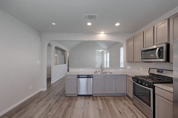 a kitchen with stainless steel appliances granite countertop a stove cabinets and wooden floor
