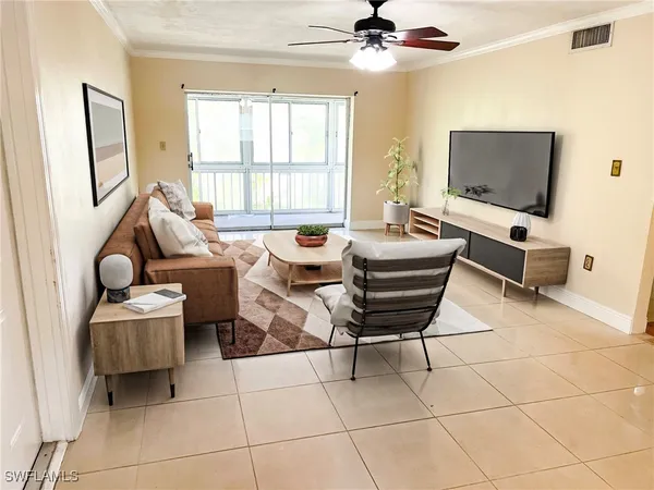 a living room with furniture a flat screen tv and a window